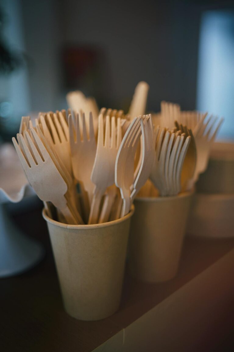 Close-up of eco-friendly wooden forks placed in paper cups on a table, creating a sustainable tableware display.