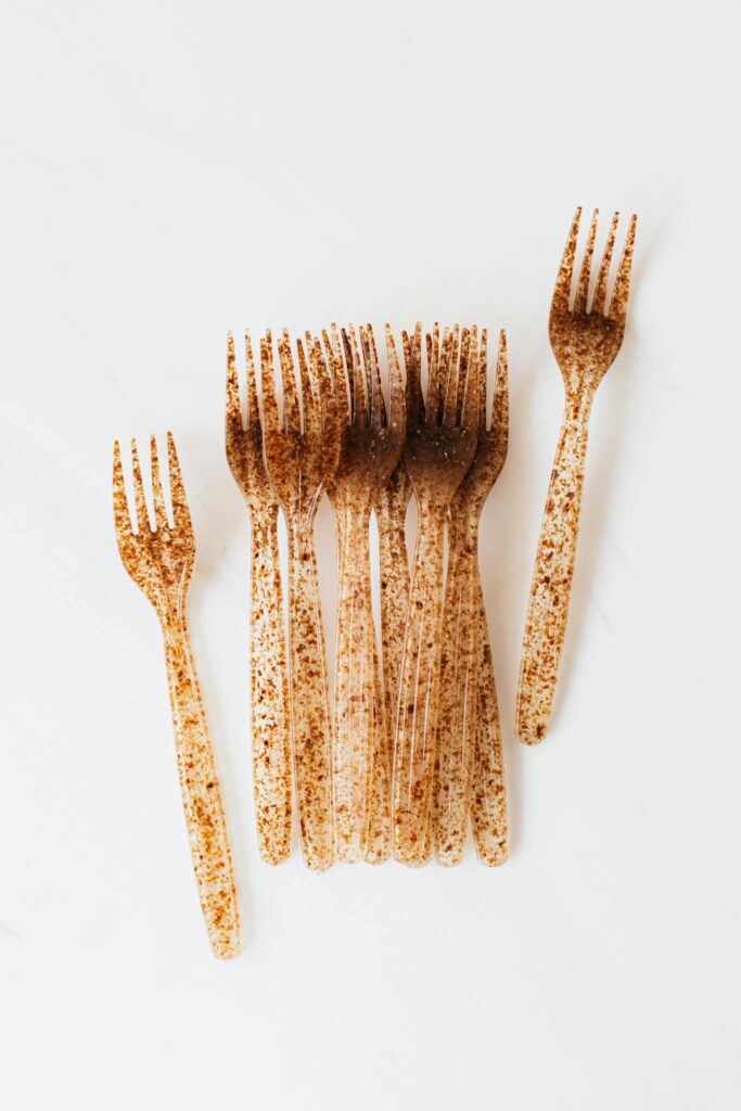 Top view of identical forks made of transparent speckled plastic placed on a white surface